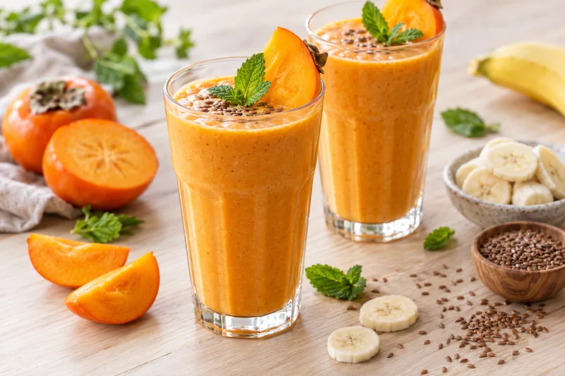 Veganer Kaki-Smoothie in Gläsern mit frischer Kaki und Banane dekoriert