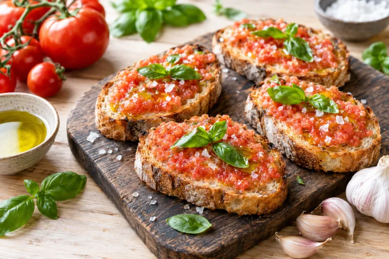 Veganes Pan con Tomate auf rustikalem Holzbrett mit frischen Tomaten und Basilikum