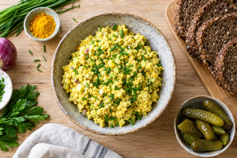 Veganer Eiersalat in einer Schüssel, garniert mit Schnittlauch und serviert mit Brot