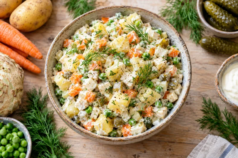 Veganer Kartoffelsalat (Sałatka Jarzynowa) in einer Schüssel mit Dill garniert