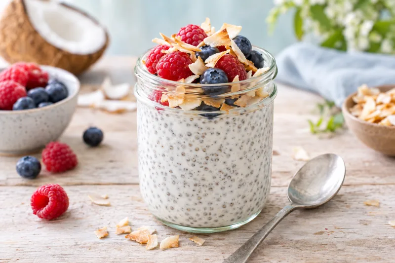 Veganer Chia-Kokos-Pudding im Glas mit frischen Beeren und gerösteten Kokosflocken