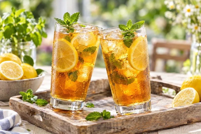 Gläser mit Ingwer-Agavendicksaft-Eistee, garniert mit Zitrone und Minze