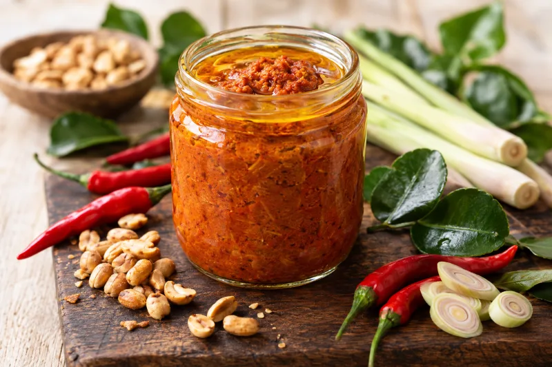 Vegane Panang Currypaste in einem Glas mit Erdnüssen und Chilis