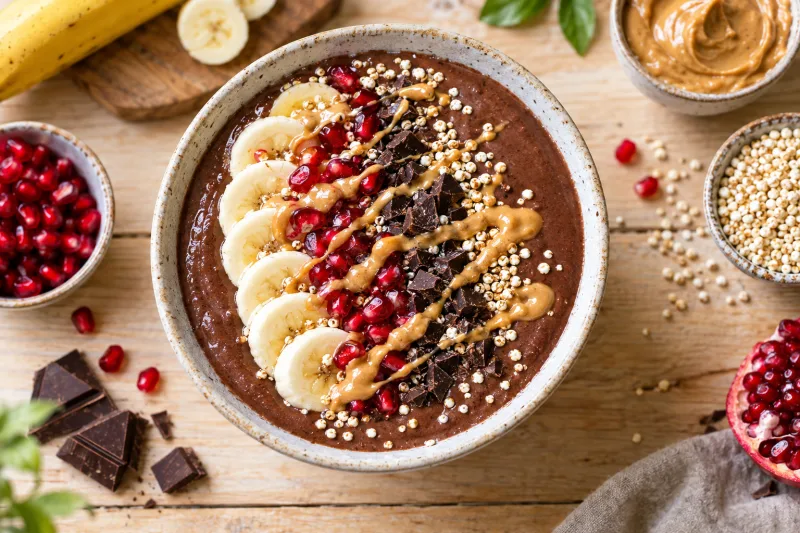Vegane Schoko-Banana-Smoothie Bowl mit Bananenscheiben, Granatapfel und Schokostückchen