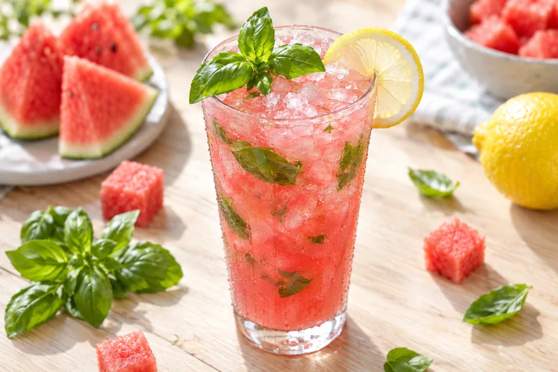 Glas mit rosa Basilikum-Wassermelonenlimonade, Eiswürfeln und Basilikumblättern garniert