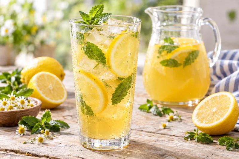 Glas mit eiskalter Kamillen-Honig-Limonade, Zitronenscheiben und Minze
